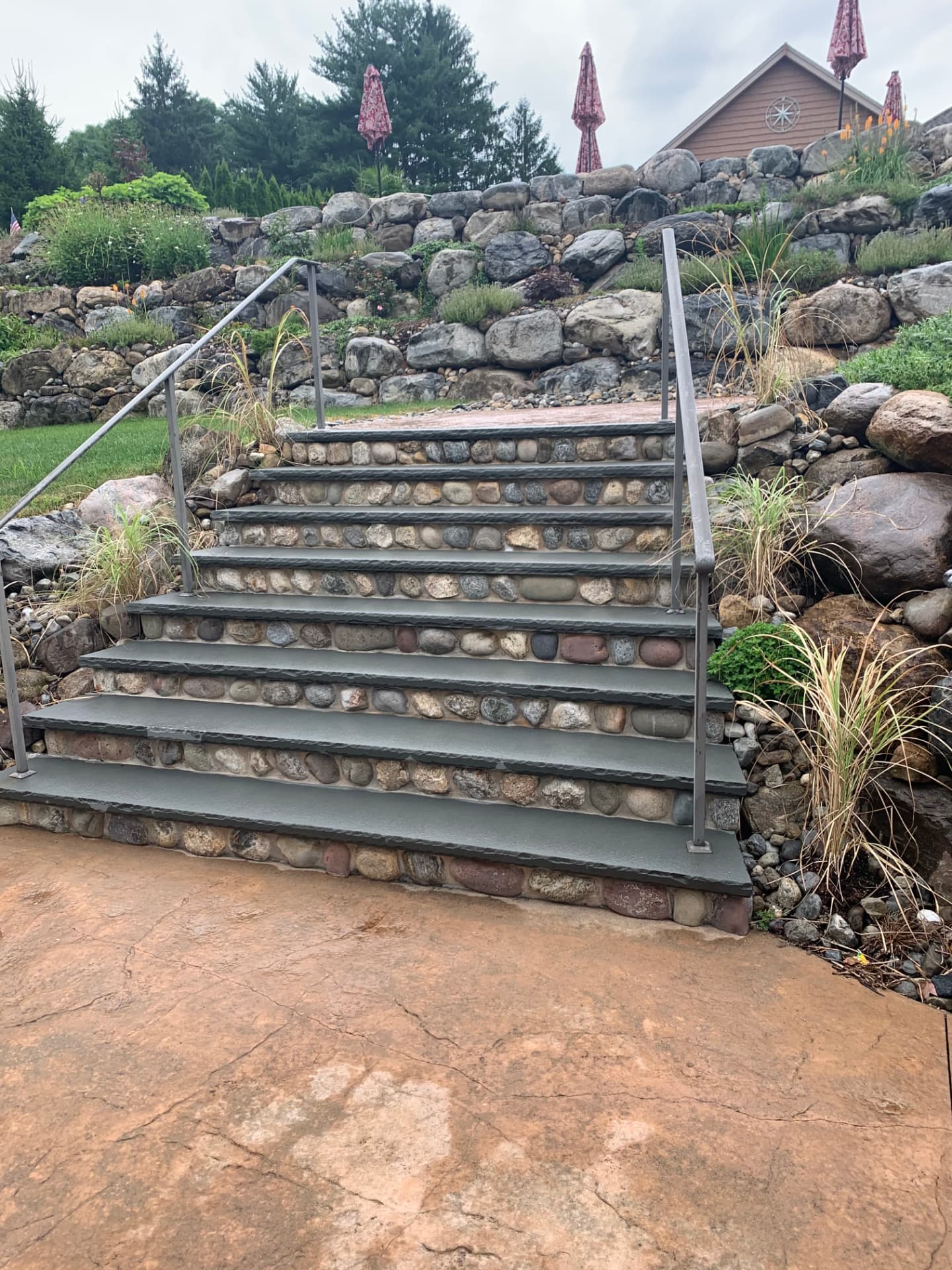 Concrete steps with river stone risers leading up a landscaped slope