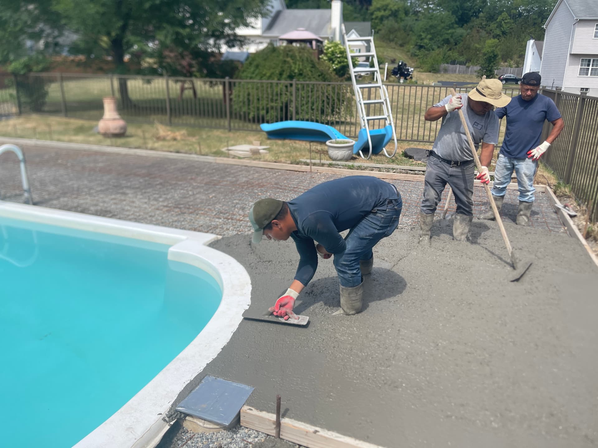 Crew finishing a concrete pool deck