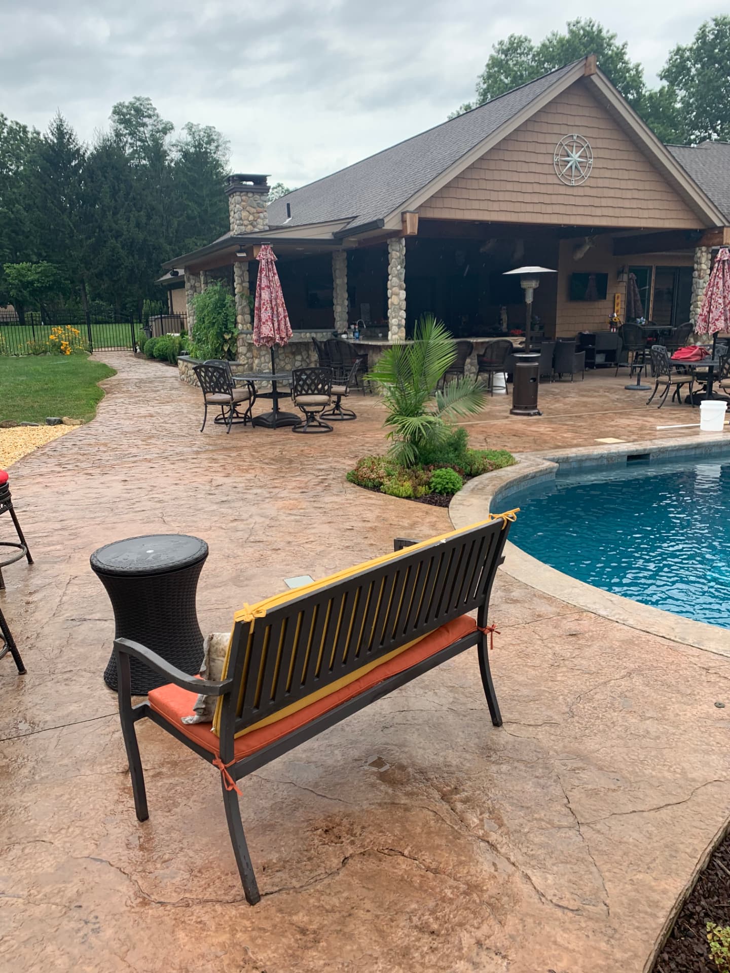 Tan stamped concrete poolside patio beside a covered outdoor kitchen