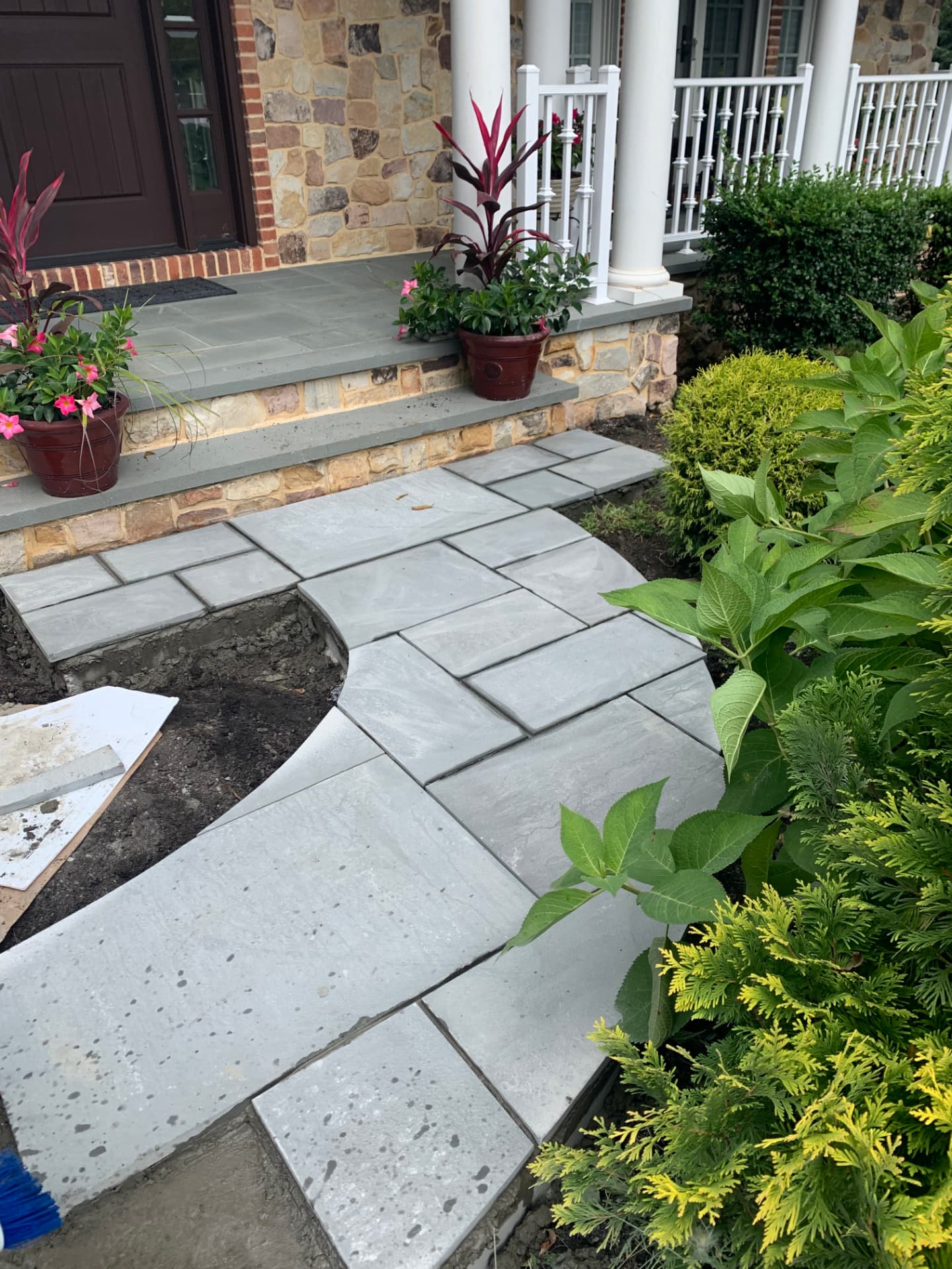 Bluestone front walkway with curved edge leading to a stone porch