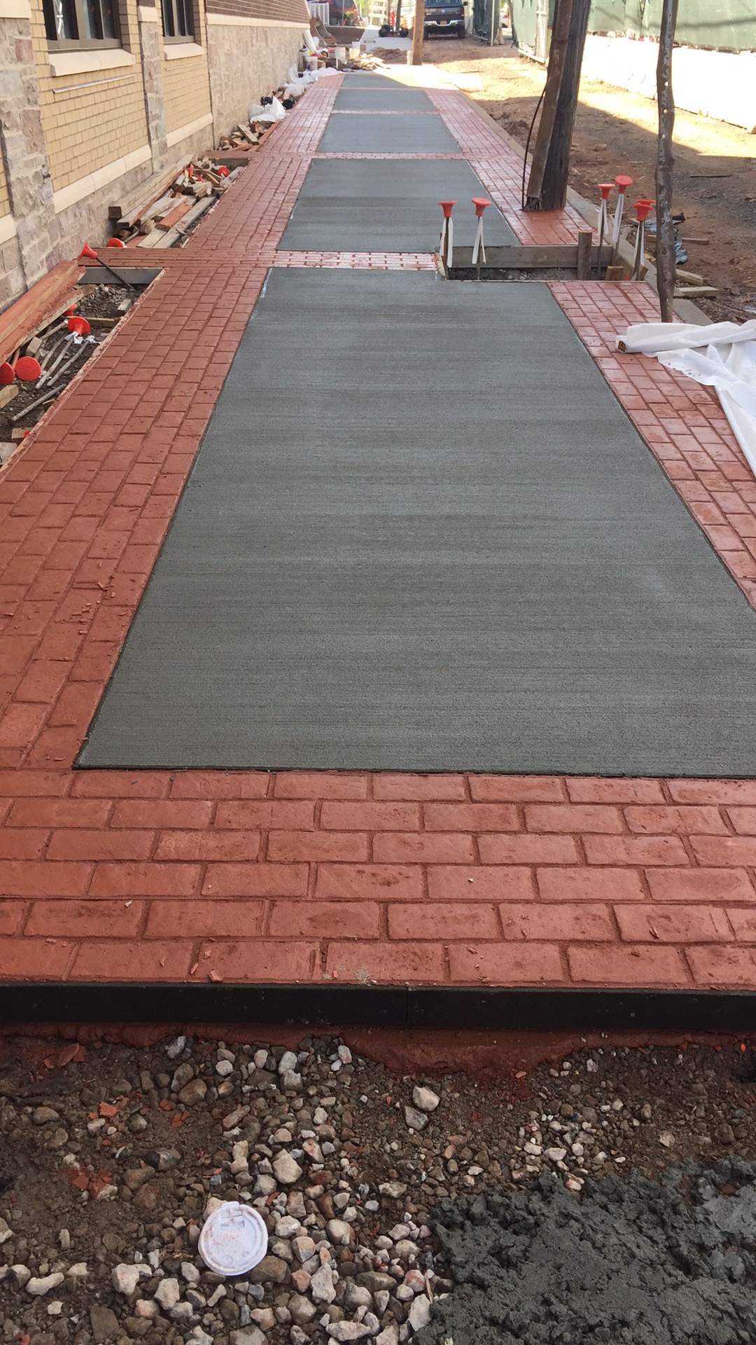 Broom finish sidewalk with red brick stamped border