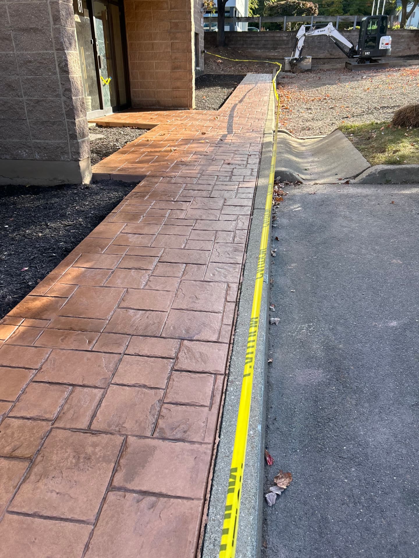 Red brick stamped concrete walkway along a commercial building