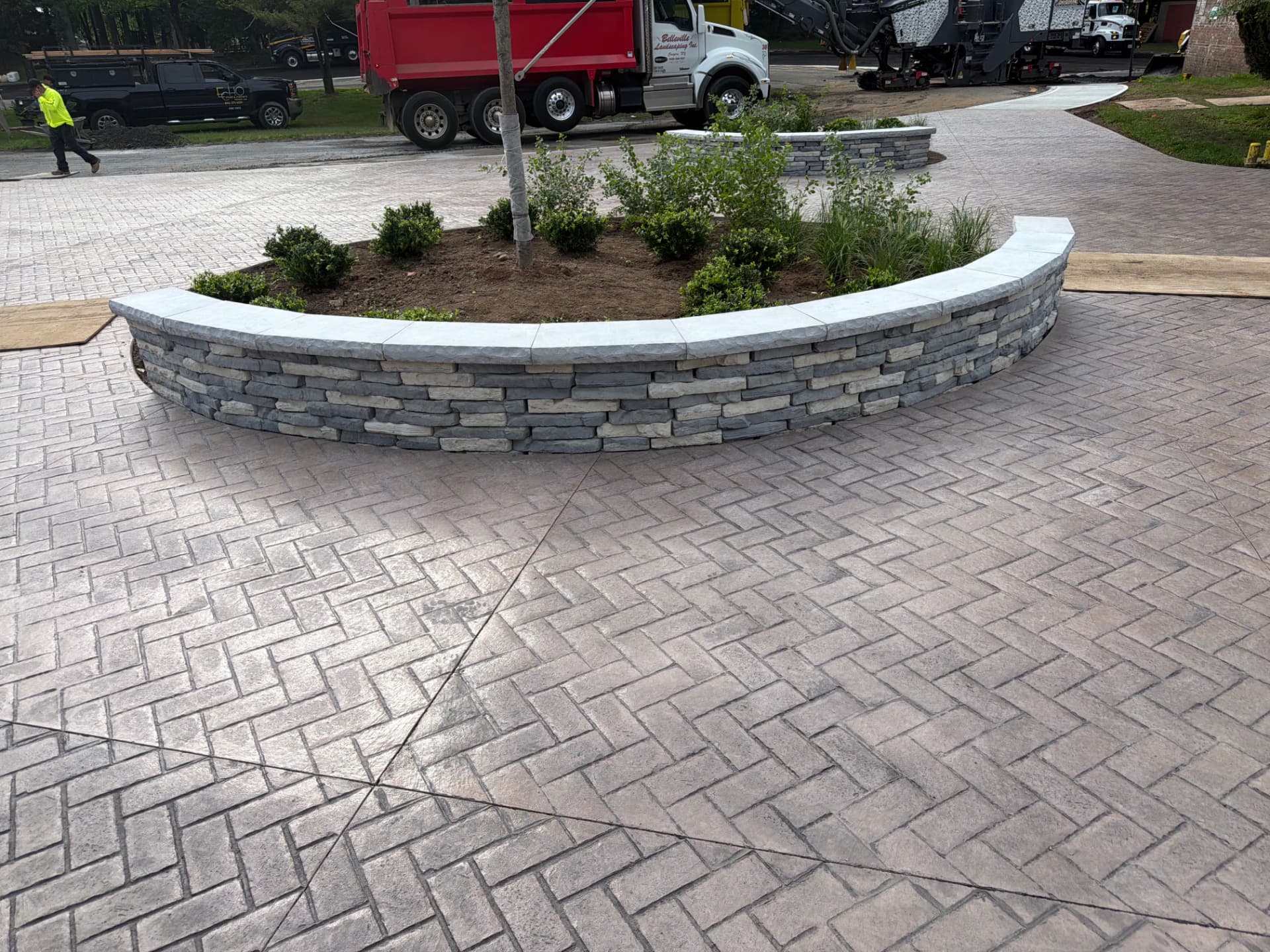 Curved stone seat wall with bluestone cap in stamped courtyard
