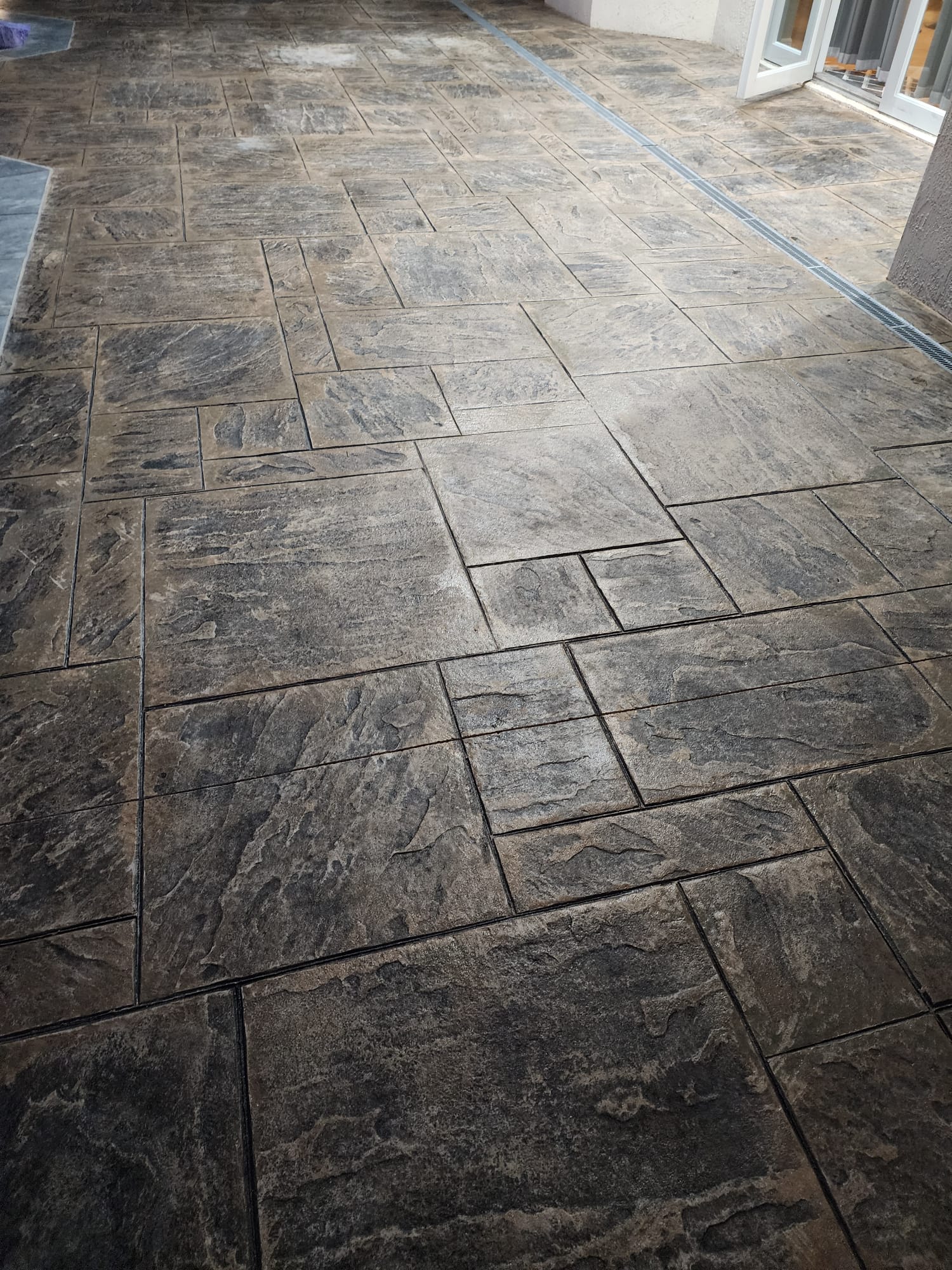 Large ashlar slate stamped concrete floor with drain