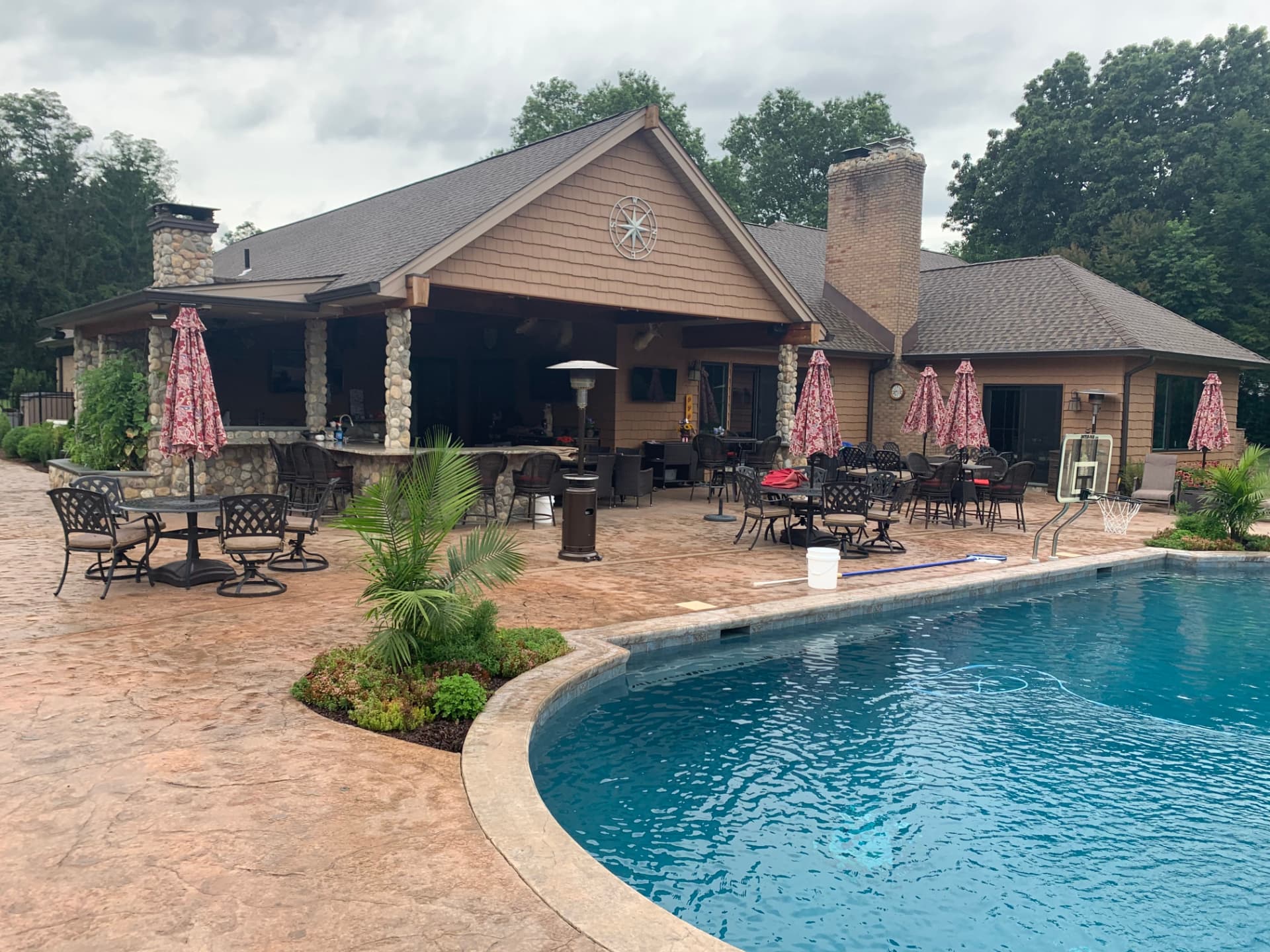 Large stamped concrete pool deck in front of a pool house