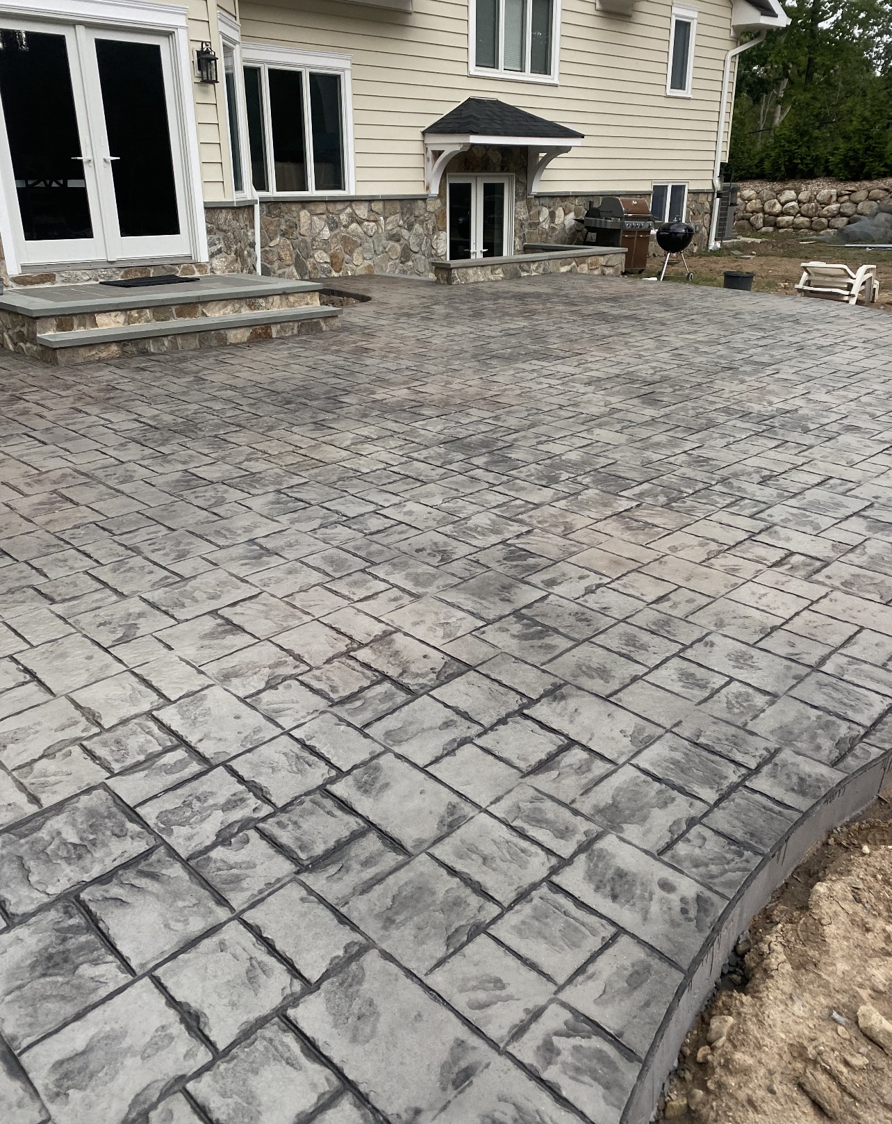 Wide cobblestone stamped concrete patio behind a home